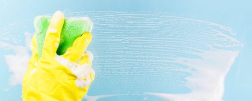 Careers Washing windows and glass. The worker in a yellow glove can stack a sponge with foam on a blue background